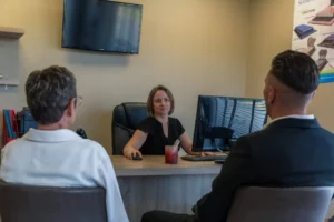 Conseillère funéraire assise à son bureau en train de recevoir deux personnes pour un entretien.